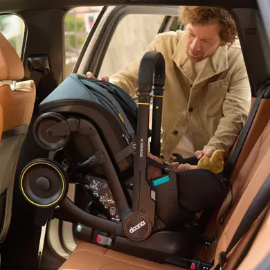 Papa installiert die Doona Babyschale sicher im Auto