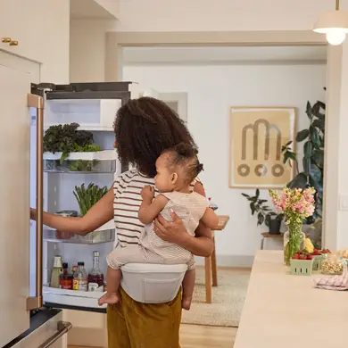 Mama mit Kind in der Küche mit der neuen Ergobaby Lift Hüfttrage