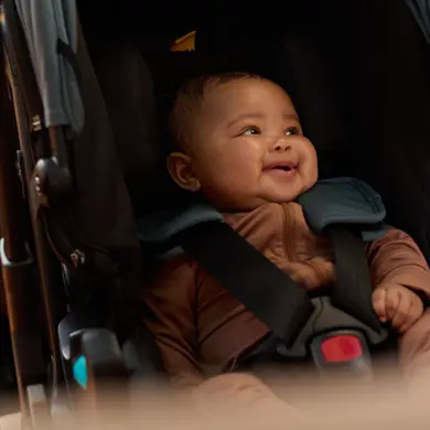 Baby sitzt lachend in der Doona Babyschale, glücklich und sicher
